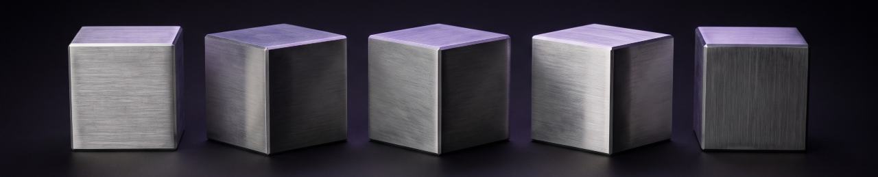 Five machined aluminium cubes in a row, each rotated further than the last